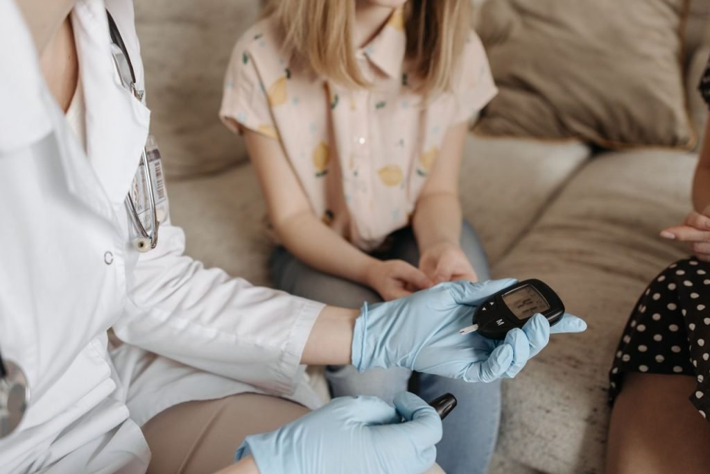 Doctor using a glucose meter to check a patients blood sugar during a medical consultation.